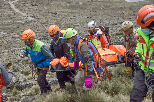 Mountain rescue team carrying a patient on a litter across rocky high country