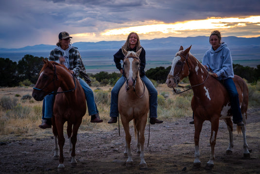 Three riders on horseback at sunset