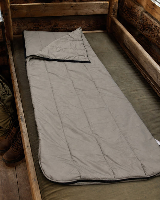 Wiggy's Slumber Bag in Gray laid out on a wooden bunk